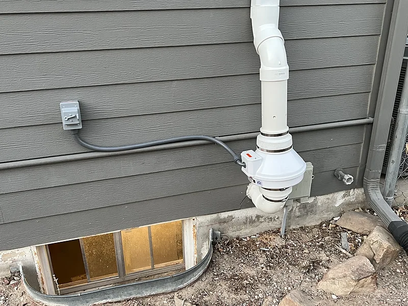 Newly installed exterior radon fan at the foundation